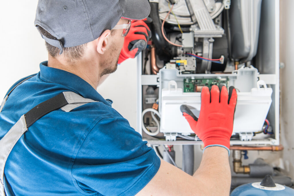 Male technician inspecting a central gas furnace.