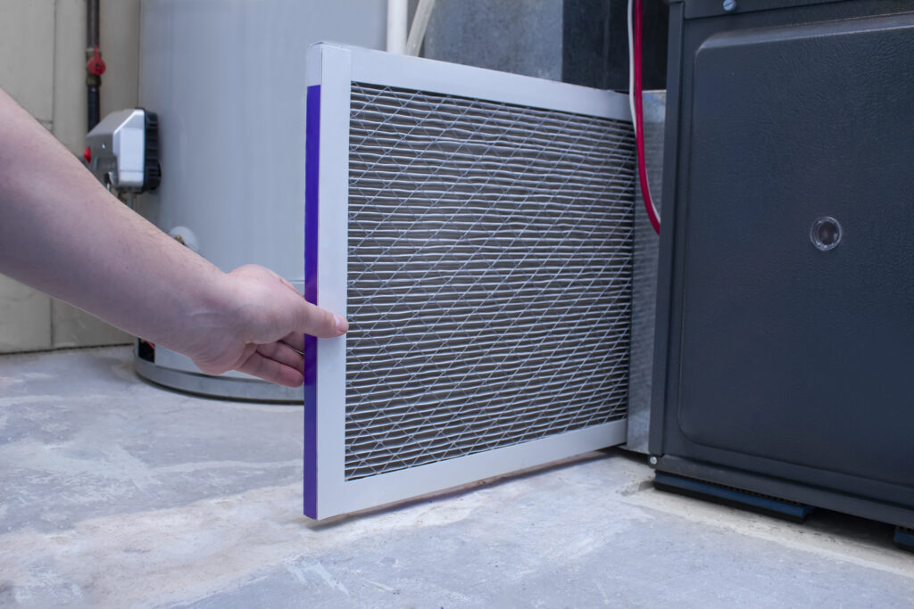 A person changing an air filter on a high-efficiency furnace